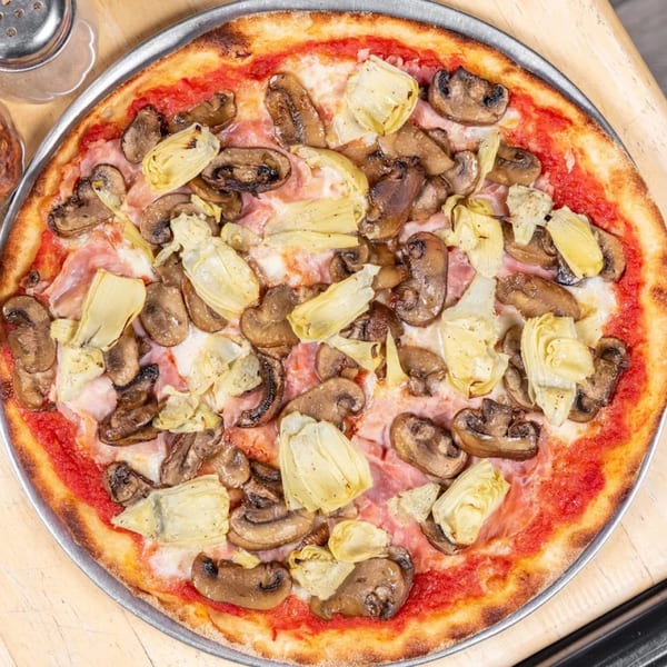L'arte Della Pizza Brooklyn's pizza with mushrooms, artichokes, and ham on a metal tray.